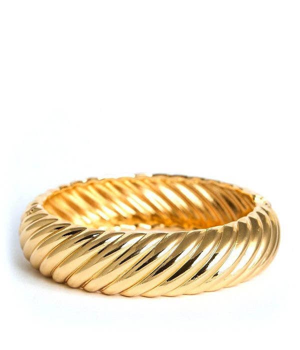 Gold cuff bracelet with ribbed design on a white background